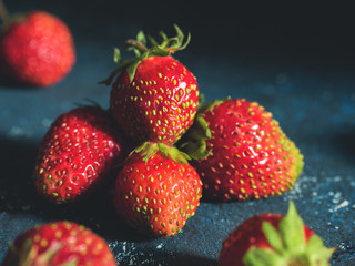 Ugly garden fresh ripe strawberry on a dark blue background. Real organic food
