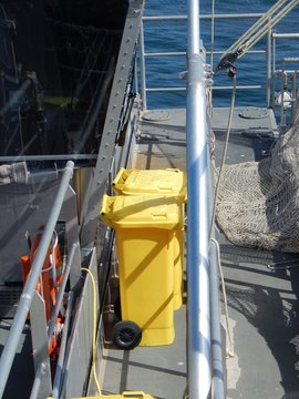 Yellow trash cans and a white fishing net aboard a ship of fishery