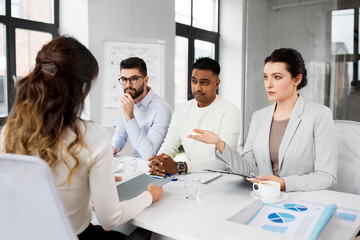 new job, hiring and employment concept - international team of recruiters having interview with female employee at office