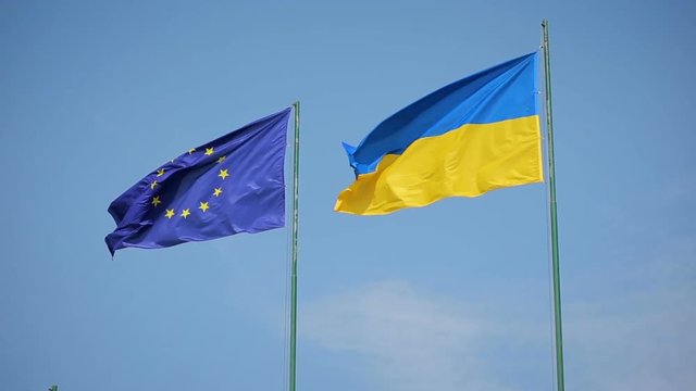 Flag of Ukraine and flag of European Union fluttering on a background of a blue sky