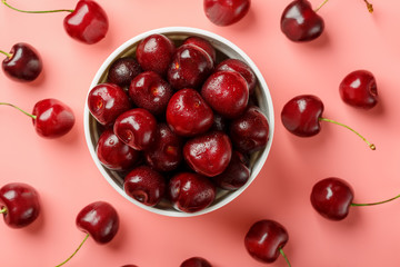 Cherry berry on a pink background in a white cup, top view.