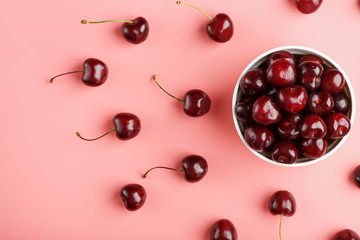 Cherry berry on a pink background in a white cup, top view.