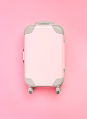 Pink suitcase on a pink background. Minimalism.