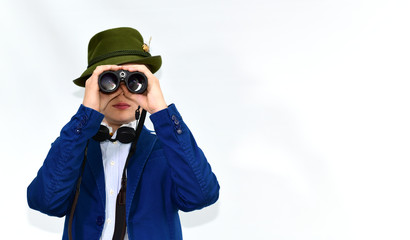 Young guy with huntsman's hat looking through binoculars over isolated background with a serious face standing with a confident expression.