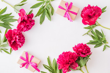 Flat lay composition with red peonies and gift box on a white background