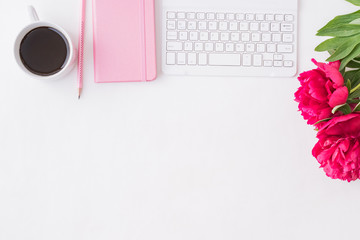 Flat lay blogger or freelancer workspace with a notebook, keyboard, red peonies on a white background