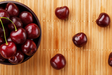 Ripe and juicy cherry berries on a wooden background in a brown cup