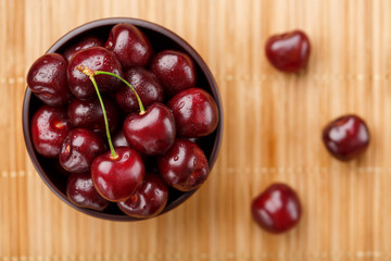 Ripe and juicy cherry berries on a wooden background in a brown cup