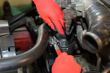 Mechanik odkręca filtr oleju w samochodzie osobowym. - obrazy, fototapety, plakaty