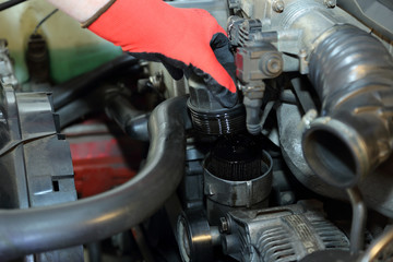 Fototapeta na wymiar Mechanik wyjmuje obudowę filtr oleju w samochodzie osobowym.