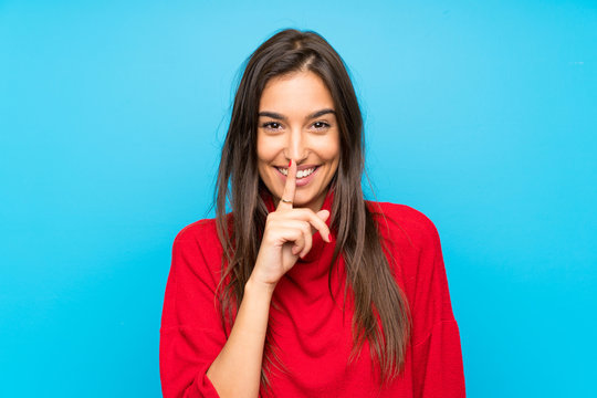 Young woman with red sweater over isolated blue background doing silence gesture