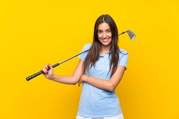 Young golfer woman over isolated yellow wall looking up while smiling