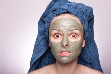 young woman in a towel on her head and mask on her face