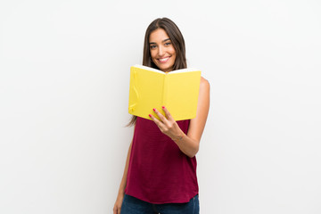 Young woman over isolated white background holding and reading a book
