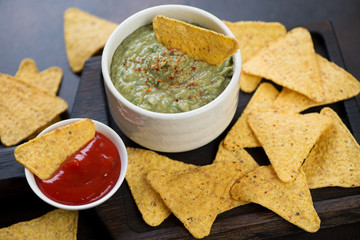 Closeup of guacamole dip with nachos, horizontal shot, selective focus