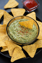 Close-up of freshly made guacamole sauce with nachos chips, vertical shot, selective focus