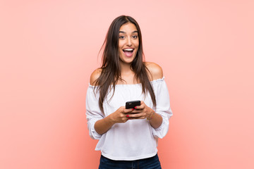 Young woman over isolated pink background surprised and sending a message
