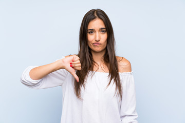 Fototapeta premium Young woman over isolated blue background showing thumb down sign