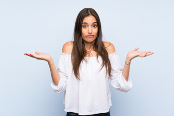 Young woman over isolated blue background having doubts with confuse face expression