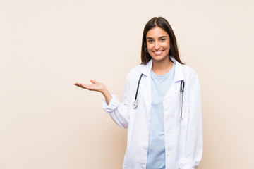 Young doctor woman over isolated background holding copyspace imaginary on the palm