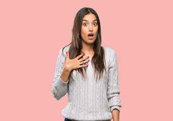 Young hispanic brunette woman surprised and shocked while looking right over isolated background