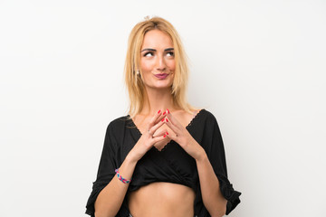 Young blonde woman over isolated white wall scheming something