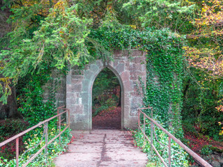 Overgrown archway at the end of a bridge