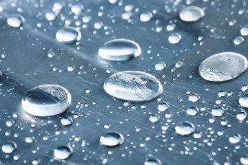 Close-up of raindrops of different sizes on the surface covered with cling film. Moisture weather and humidity concept