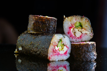 Sushi rolls on a black mirror background.