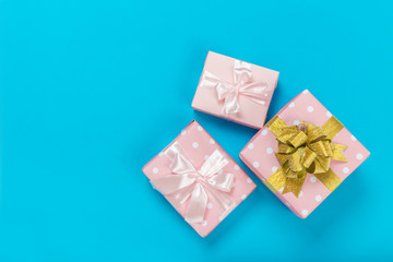 beautiful gift boxes wrapped in paper with gold and pink ribbon on a blue surface. Top view