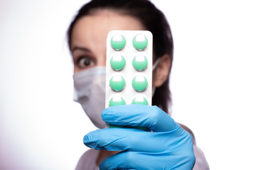 young woman in a medical poppy and gloves with a pills