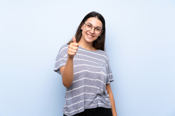 Young brunette woman over isolated blue background with glasses