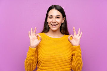 Young woman over isolated purple background showing an ok sign with fingers