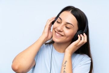 Young woman listening music over isolated blue background