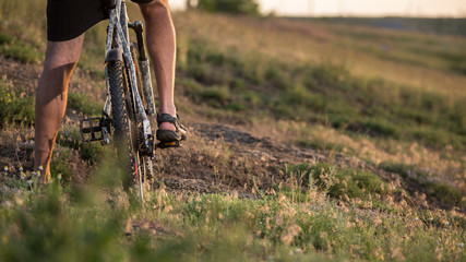 Cyclist riding the bike down rocky hill at sunset. Close up extreme sport concept	