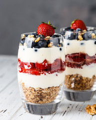 Two pieces of puff glass dessert with granola, mascarpone cream, strawberry, blueberry and walnuts