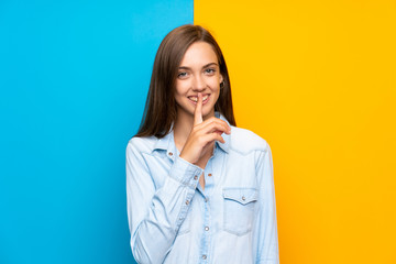 Young woman over colorful background doing silence gesture