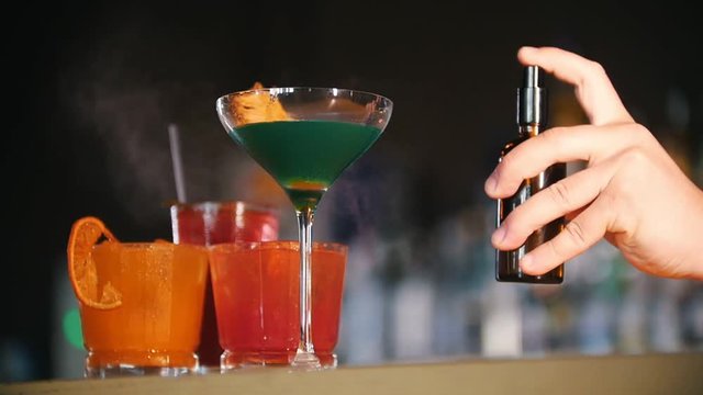 Bar concept. Young professional bartender sprays a cocktail with a special flavoring.