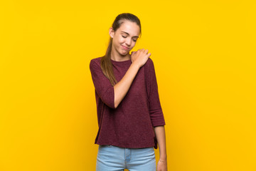 Young woman over isolated yellow background suffering from pain in shoulder for having made an effort