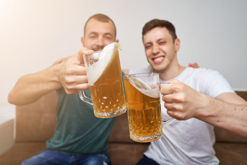 Friends watching Tv  while eating chips popcorn and drinking some cold beer