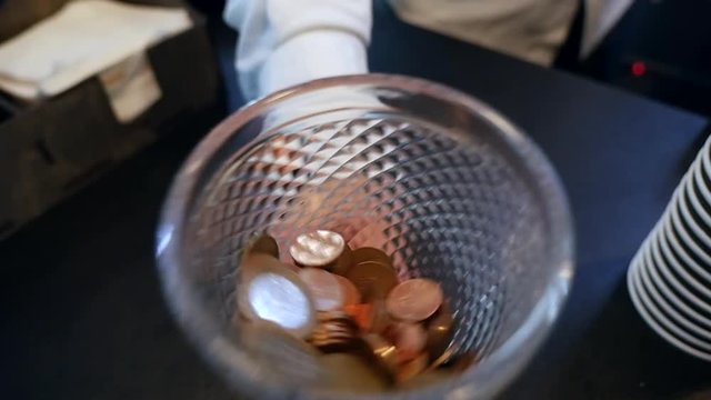 Coins and money of different countries in a glass vase.