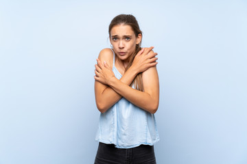 Young woman over isolated blue background freezing