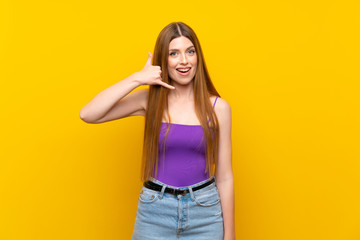 Fototapeta premium Young woman over isolated yellow background making phone gesture. Call me back sign
