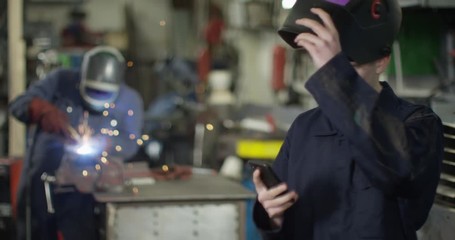 4K Young mechanic in garage workshop talking to a customer on the phone