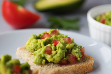 Toasts with an avocado snack and fresh vegetables on a gray background.