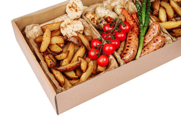 Sausage Potato Fresh Tomato Box Delivery Closeup. Grilled Different Variety Meat Dish Pork and Beef Banger, Garlic and Green Vegetable in Paper Package Isolated on White Background. Delicious Present