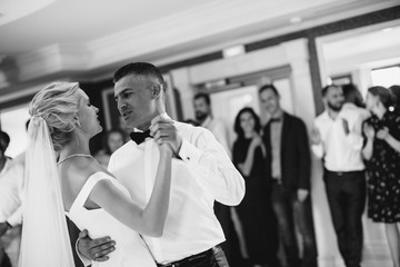 A bride and a groom are dancing together. Black and white image.