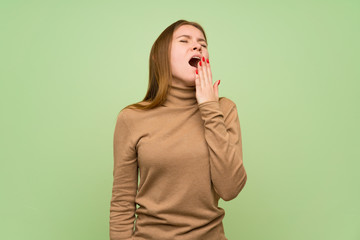 Young woman with turtleneck sweater yawning and covering wide open mouth with hand