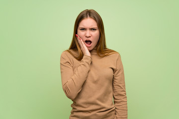 Young woman with turtleneck sweater surprised and shocked while looking right