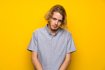 Fototapeta premium Blonde man over isolated yellow background with sad and depressed expression